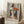 May include: Framed abstract portrait artwork in Picasso's cubist style showing a woman with geometric orange and teal hat, displayed leaning against white wall corner on fluffy white rug. Coffee cup sits on wooden block nearby, with beige blanket draped in corner. Natural window light creates soft shadows on the neutral-toned room setting.