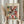 May include: Person holding framed Paul Klee art print featuring colorful geometric squares in reds, greens, purples, and yellows with small tree motifs. Light wood frame against neutral beige clothing and dried wheat stems. Soft natural lighting creates warm, minimalist styling.
