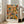 May include: Framed abstract expressionist artwork with vibrant orange, blue, yellow and green paint splatters and drips in Pollock's signature style, displayed on light wooden floors against white walls next to a beige upholstered sofa in a bright, naturally-lit living room with tall windows.