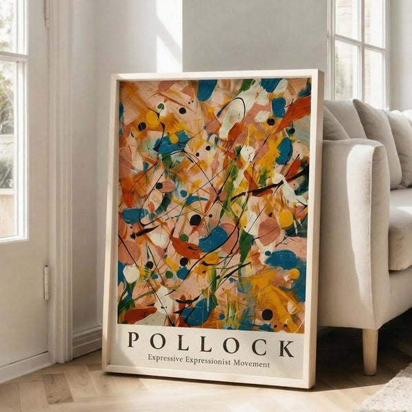 May include: Framed abstract expressionist artwork with vibrant orange, blue, yellow and green paint splatters and drips in Pollock's signature style, displayed on light wooden floors against white walls next to a beige upholstered sofa in a bright, naturally-lit living room with tall windows.