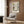 May include: Framed Piet Mondrian abstract art print featuring geometric black lines with yellow and red rectangles on cream background, displayed on wood paneled wall above beige upholstered chair with patterned pillow, brass floor lamp and side table with open book nearby