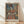 May include: Framed art print featuring a woman in colorful traditional dress with red bodice, striped skirt, and decorative hat, painted in Picasso-inspired cubist style with muted blues and warm oranges. The poster sits against a white wall on light wooden flooring, displayed in a simple wooden frame with natural lighting casting soft shadows.
