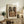 May include: Framed Picasso cubist artwork showing abstract musician figure in earth tones of brown, orange and beige, displayed on rustic wooden console table alongside fern plant, ceramic vase, and books in neutral-toned living room setting with cream upholstered chair