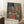 May include: Framed art print leaning against white wall on fluffy white rug, showing colorful portrait of woman in traditional dress with ornate hat. Painting features blues, oranges, and earth tones in cubist style. White coffee cup sits on wooden block nearby, soft natural lighting creates window shadows on wall.