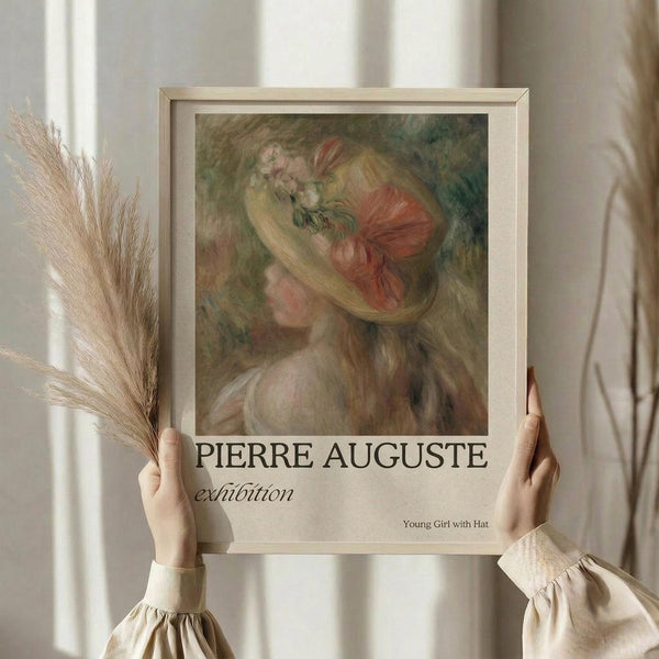 May include: Hands holding a framed vintage-style poster featuring a soft impressionist painting of a young woman with blonde hair wearing a decorative hat with pink ribbon and flowers. The artwork has muted green, pink and cream tones. Below the painting is text reading "PIERRE Auguste exhibition" and "Young Girl with Hat." Person wears cream colored clothing with puffy sleeves and holds dried wheat stems. Neutral beige curtained background creates soft natural lighting.
