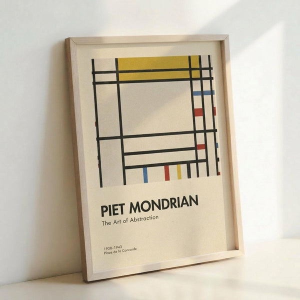 May include: Framed poster print leaning against white wall showing abstract geometric composition with black grid lines, yellow rectangle at top, small red and blue rectangles, cream background. Text reads "PIET MONDRIAN The Art of Abstraction 1938-1943 Place de la Concorde" in black letters below artwork. Light wood frame visible.