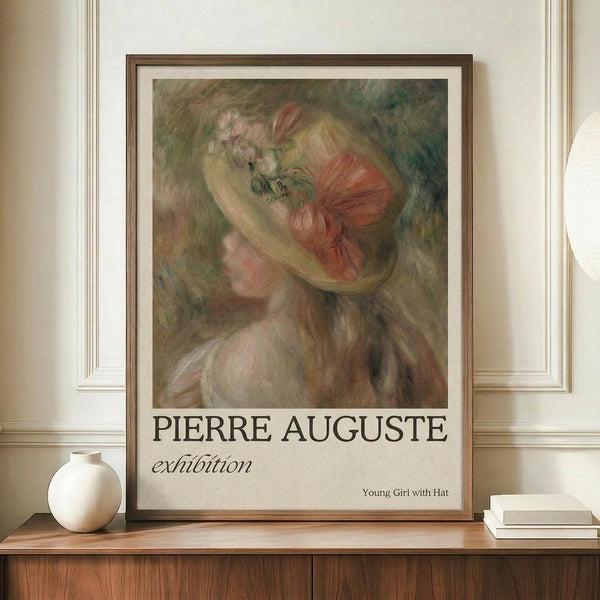 May include: Exhibition poster featuring impressionist-style painting of young woman with flowing blonde hair wearing coral-pink hat with flowers, rendered in soft brushstrokes with muted green background. Framed print displayed on wooden sideboard alongside white ceramic vase and stacked books in elegant room with cream walls and traditional molding.