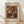 May include: Framed art print of Pierre Auguste Renoir's 1919 floral painting showing vibrant orange and red flowers with white chrysanthemums in a blue and white ceramic vase. The impressionist-style bouquet features warm autumn colors against an earthy brown background. Light wood frame with cream matting displays the artwork against a white wall on light wooden flooring with natural sunlight casting diagonal shadows.