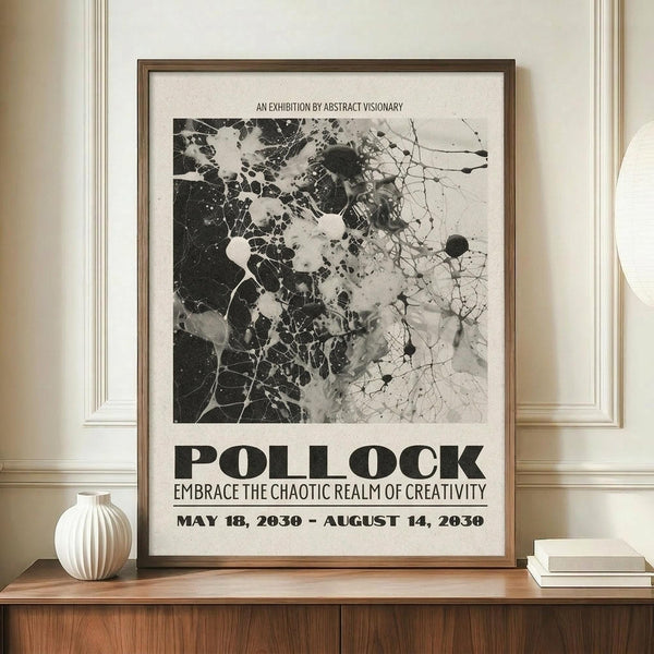 May include: Framed black and white abstract art poster with splattered paint design mounted on cream wall above wooden sideboard. White ribbed ceramic vase and stack of books sit beside the brown wooden frame. The poster features bold text reading "POLLOCK" and exhibition details with dates. Abstract expressionist style artwork shows dynamic paint splatters and organic forms in monochrome palette.