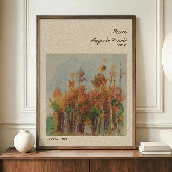 May include: Framed art print displaying an impressionist-style painting of autumn trees with orange, red, and green foliage against a pale blue sky. The artwork features warm earth tones and loose brushstrokes typical of impressionist technique. Shown in a thin brown wooden frame with cream matting, displayed on a wooden sideboard next to a white ceramic vase and stacked books in an elegant room with white wainscoting and cream walls.