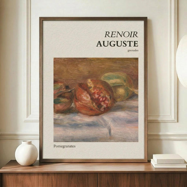 May include: Framed art print featuring Renoir's impressionist painting of ripe pomegranates in warm red and green tones on white background with black text, displayed on wooden sideboard next to small white ceramic vase and stacked books against cream paneled wall