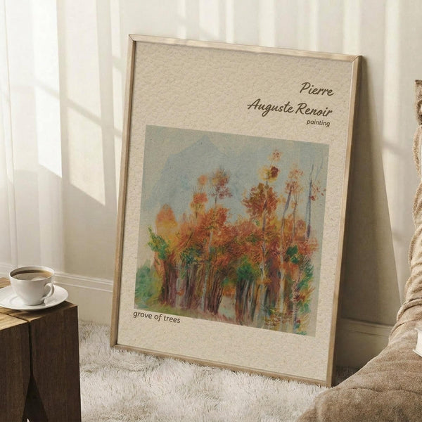 May include: Framed art print of autumn trees with orange and green foliage against a pale blue sky, displayed in a light wood frame on a white textured rug. The impressionist-style painting shows a grove of trees in fall colors. A white coffee cup sits on a wooden block nearby, with soft natural lighting creating shadows on the white wall behind.