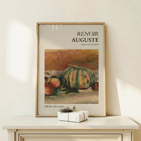 May include: Framed art print featuring Renoir's still life painting of a striped green and yellow melon with peaches on a table, displayed on light wood furniture with a small white wrapped gift beside it. Warm earth tones throughout the classical impressionist artwork in natural wood frame against cream wall.
