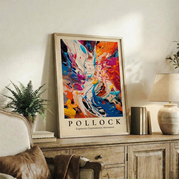May include: Framed abstract art print with vibrant swirling colors in blues, oranges, reds, and yellows displayed on rustic wooden sideboard. Scene shows cream chair with brown throw pillow, potted fern, stacked books, ceramic vase, and neutral wall background creating cozy living room setting.