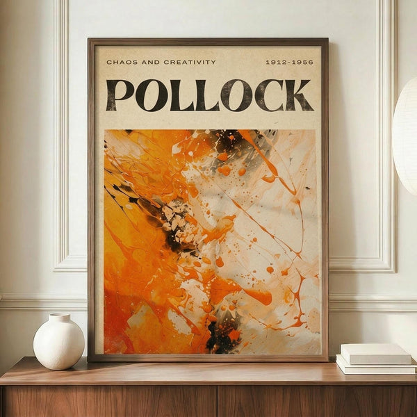 May include: Framed abstract art print in warm orange, white, and dark tones with paint splatters and dynamic brushstrokes, displayed on wooden sideboard next to white ceramic vase and stacked books. The poster features "POLLOCK" in bold black letters above the artwork with "CHAOS AND CREATIVITY 1912-1956" header text. Modern interior setting with white paneled walls and neutral decor.
