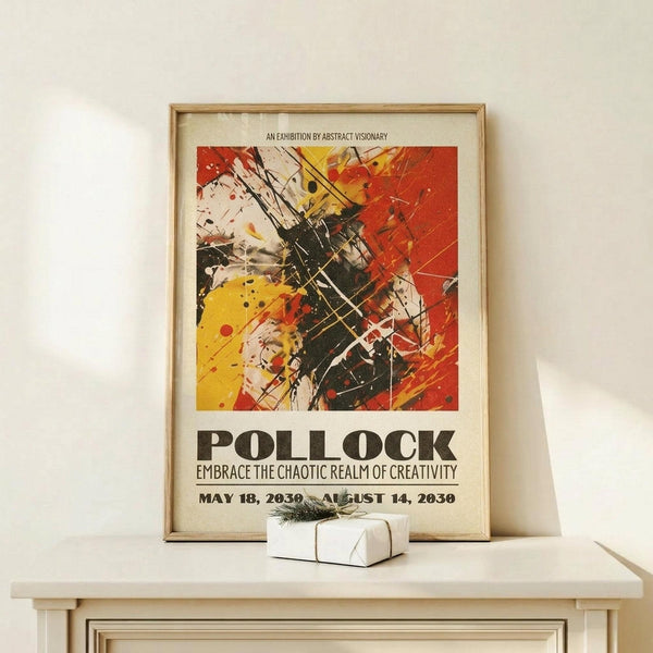 May include: Framed abstract art poster in light wood frame leaning against white wall on natural wood shelf. Features vibrant splattered paint design with red, yellow, black and white colors in Jackson Pollock style. Text reads "POLLOCK" and "EMBRACE THE CHAOTIC REALM OF CREATIVITY" with exhibition dates. Small white wrapped gift box with twine and pine sprig sits beside frame.