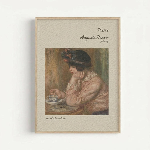 May include: Framed art print displaying Pierre-Auguste Renoir's painting of a woman in a pink dress and dark feathered hat, seated at a table with a blue and white teacup. The reproduction shows warm, soft brushstrokes typical of Impressionist style. Light wood frame with cream matting displays text identifying the artist and artwork title. Wall-mounted against neutral background.