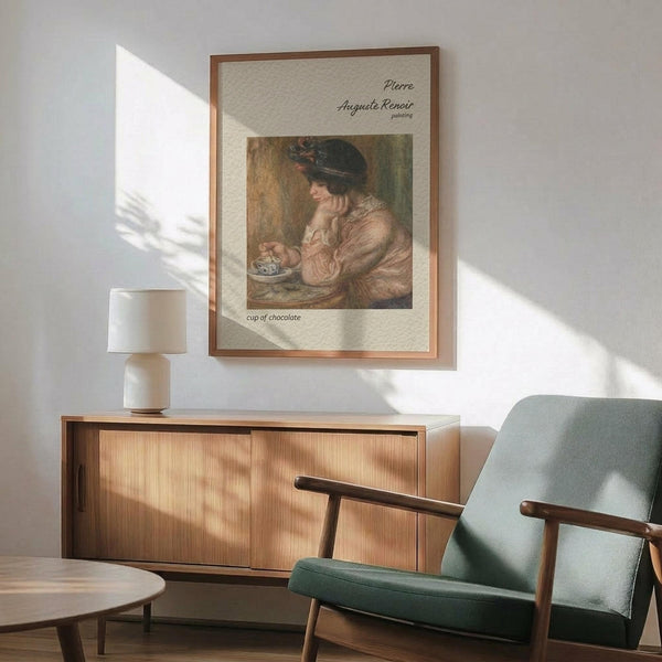 May include: Framed vintage Renoir reproduction showing woman in hat enjoying chocolate, displayed on white wall above mid-century wooden credenza with ceramic lamp. Sage green upholstered armchair with wooden frame sits nearby on hardwood floor. Warm natural sunlight creates geometric shadows across the minimalist room setting.