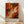May include: Abstract expressionist art poster with swirling orange, red, white and black paint strokes in energetic fluid motion, displayed in thin wooden frame leaning against white textured wall on light wood floor with soft natural lighting creating diagonal shadows