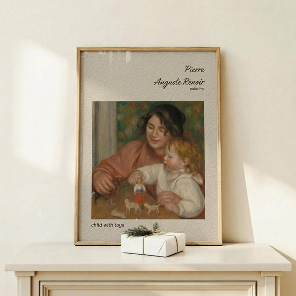 May include: Framed art print of Renoir's "Child with Toys" painting showing woman in rust-colored dress with blonde child playing with small figurines, displayed on light wood console table next to white wrapped gift with evergreen sprig, against cream wall with natural lighting