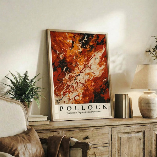 May include: Abstract expressionist art print with vibrant orange, red, black and white paint swirls in light wood frame, displayed on rustic wooden sideboard alongside fern plant, books, ceramic vase and lamp in cozy living room setting with beige armchair