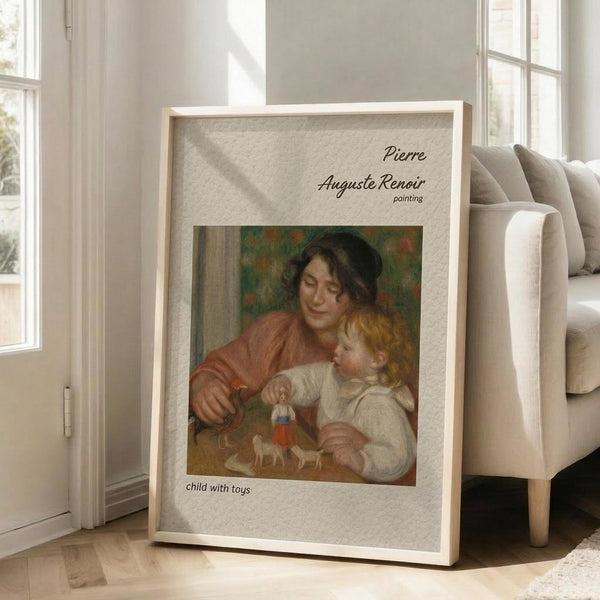 May include: Framed art print leaning against beige armchair in bright living room with white walls and windows. Print shows Renoir painting of woman in reddish dress holding blonde child playing with colorful toys. Light wood frame with wide cream matting displays museum-style poster format with artist name and artwork title in elegant typography.