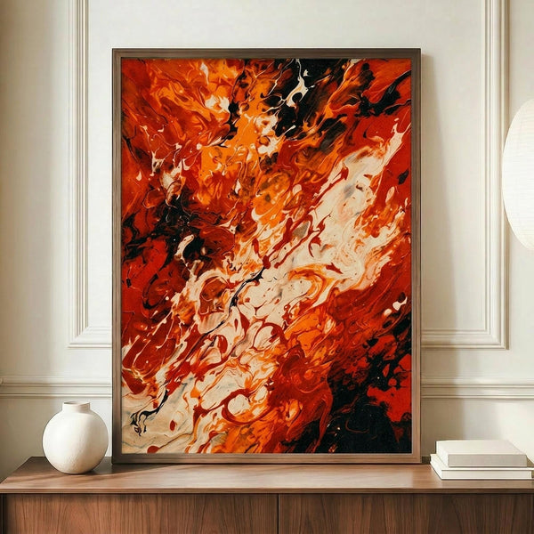 May include: Abstract expressionist painting with dynamic swirls of orange, red, white and black paint in an energetic, flowing composition. The artwork is displayed in a thin dark frame on a wooden console table alongside a white ceramic vase and stack of books against cream paneled walls.
