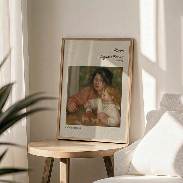May include: Framed art print of Renoir's "Child with Toys" painting showing a woman in reddish-brown clothing holding a blonde child in white, displayed on a round wooden side table next to a beige upholstered chair. Soft natural light creates shadows across white walls, with green plant leaves visible in the corner.