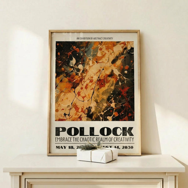 May include: Framed abstract art poster with chaotic paint splatters in warm oranges, browns, and blacks displayed on light wood shelf against cream wall. Small white gift box with twine sits beside the natural wood frame. The artwork features dynamic brushstrokes and paint drips in an expressive style with exhibition text below the image.