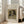 May include: Framed art print of Renoir's 1870 dog portrait showing a small spaniel-type dog with brown and white fur and dark ears wearing a collar with bell. The vintage painting has warm earth tones on aged canvas. Modern white frame leans against beige armchair in bright living room with large windows and hardwood floors.