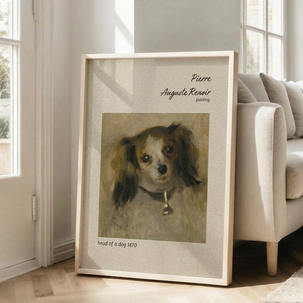 May include: Framed art print of Renoir's 1870 dog portrait showing a small spaniel-type dog with brown and white fur and dark ears wearing a collar with bell. The vintage painting has warm earth tones on aged canvas. Modern white frame leans against beige armchair in bright living room with large windows and hardwood floors.