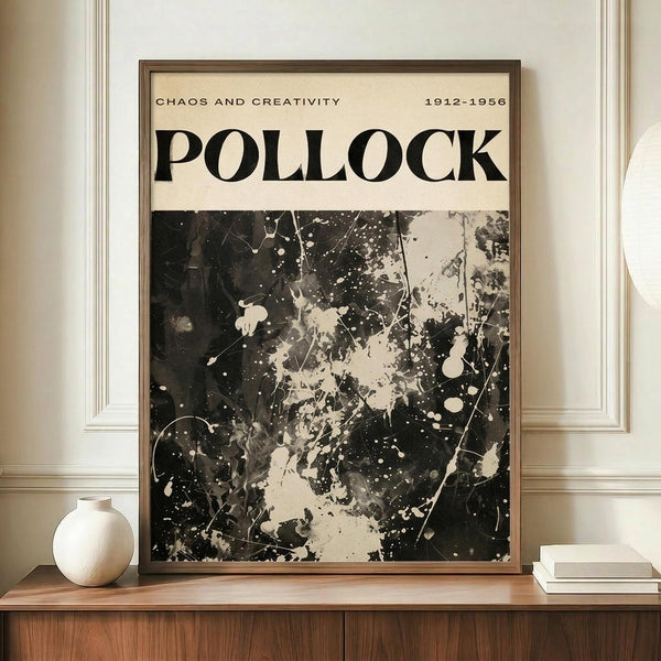 May include: Black and white abstract art poster featuring paint splatters and drips in Pollock's signature style, displayed in thin brown frame on wooden sideboard. White ceramic vase and stacked books sit nearby. Cream colored walls with white trim molding create elegant interior setting.