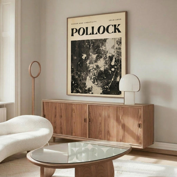May include: Black and white abstract art poster with paint splatters and drips displayed above a mid-century modern walnut credenza. Room features cream walls, white sculptural chair, glass oval coffee table, and warm wood tones throughout. Poster shows dramatic contrast with organic paint patterns against light background in thin frame.