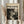 May include: Hands holding a framed poster featuring Jackson Pollock's abstract expressionist drip painting in black and white, with text reading "Chaos and Creativity" and "1912-1956" at top. Light wood frame against neutral beige clothing and dried pampas grass in soft natural lighting.