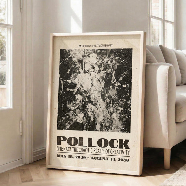 May include: Large framed exhibition poster with abstract black and white paint splatter artwork in Jackson Pollock style, leaning against white wall next to beige upholstered sofa. Natural lighting from windows creates soft shadows. Poster features bold typography reading "POLLOCK" and "EMBRACE THE CHAOTIC REALM OF CREATIVITY" with exhibition dates. Light wood frame on hardwood flooring with neutral home decor.