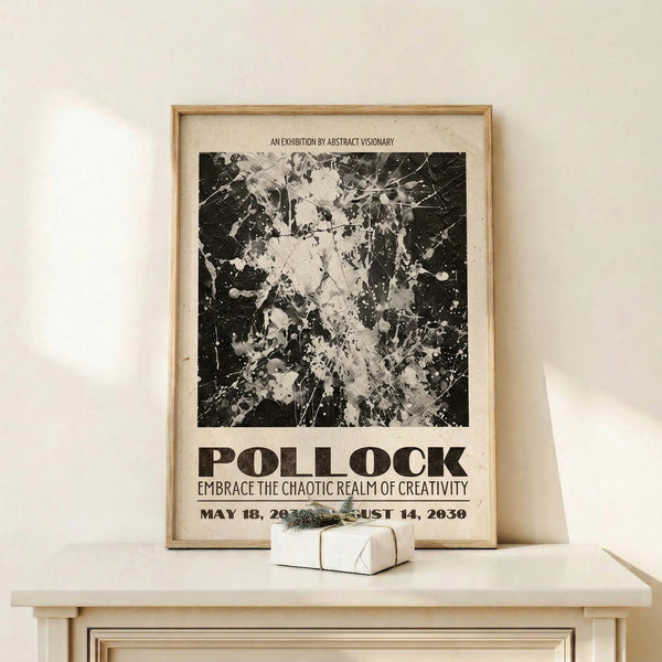 May include: Framed poster with black and white abstract splatter artwork displayed on light wood shelf against cream wall. Wood frame surrounds vintage-style exhibition poster featuring chaotic paint splatters and drips. Small wrapped gift box with greenery sits beside frame. Natural lighting creates soft shadows on minimal modern interior setting.