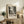 May include: Black and white abstract art poster with paint splatter design in wooden frame, displayed on rustic wooden console table alongside fern plant, books, and ceramic vase in neutral-toned living room setting