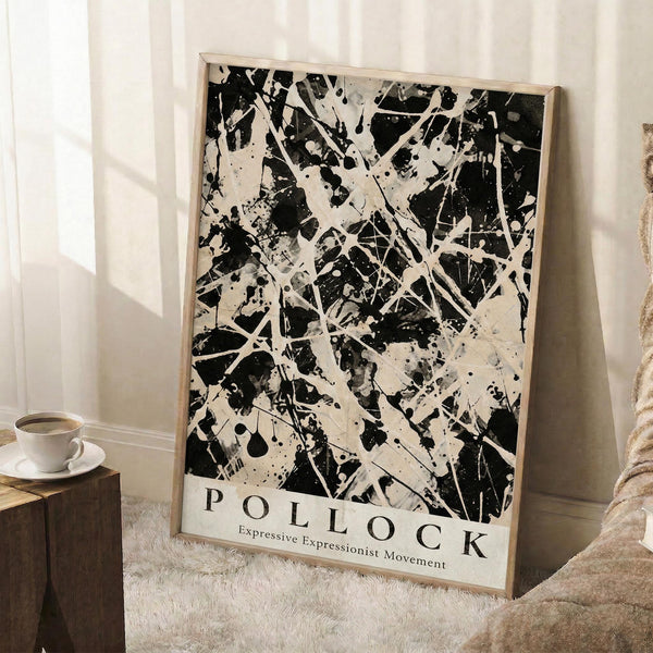 May include: Black and white abstract expressionist art print with chaotic paint splatters, drips, and gestural brushstrokes in wooden frame, leaning against white wall next to wooden stool with coffee cup and saucer, on textured cream rug beside beige blanket in bright room with window light.