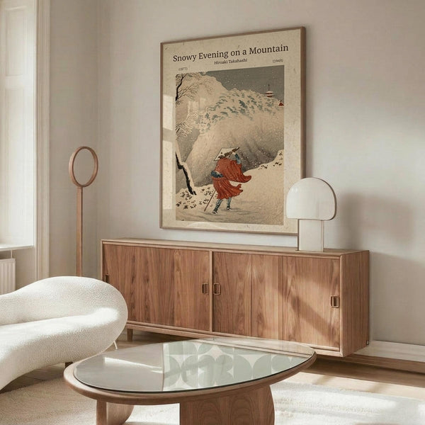 May include: Japanese woodblock print showing figure in red walking through snowy mountain landscape with bare trees, displayed in thin frame above walnut credenza in modern living room with white curved chair, glass coffee table, and brass floor lamp