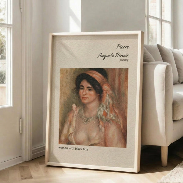 May include: A framed art print leaning against a white wall beside a beige upholstered chair. The poster features a Renoir painting of a woman with dark hair wearing a pearl necklace and flowing fabric in warm peachy tones. The print has "Pierre Auguste Renoir painting" at the top and "Woman with black hair" at the bottom on a cream background with light wood frame.