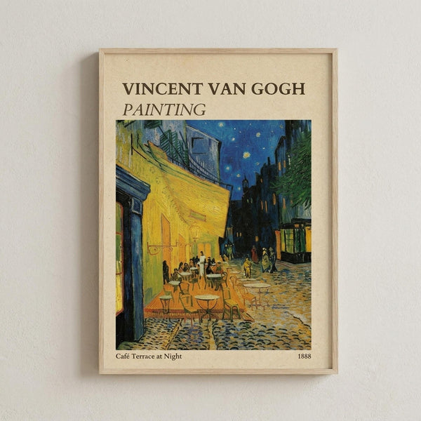 May include: Framed poster print of Van Gogh's famous café terrace night scene hanging on white textured wall. The artwork shows a yellow-lit café with outdoor seating under a starry blue evening sky, cobblestone street, and buildings in warm yellows and cool blues. Light wood frame surrounds cream-colored matting with black text identifying the artist, painting title, and 1888 date.
