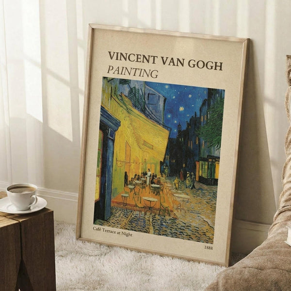 May include: Framed Van Gogh reproduction print showing Cafe Terrace at Night painting with yellow cafe, blue starry sky, and cobblestone street. Light wood frame with cream matting, leaning against white wall corner. Small wooden side table with white coffee cup and saucer nearby. Soft natural lighting creates gentle shadows on white fluffy area rug.