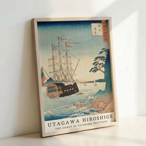 Framed Japanese woodblock print reproduction showing a large sailing ship with multiple masts and white sails on choppy blue-green ocean waters. The scene includes rocky coastline with trees on the right, stylized waves in the foreground, and gradient sky from blue to pale yellow. Japanese text characters appear in red cartouches in the upper right corner. The artwork displays traditional ukiyo-e style with flat color planes and bold outlines. Light wooden frame sits against white wall, casting