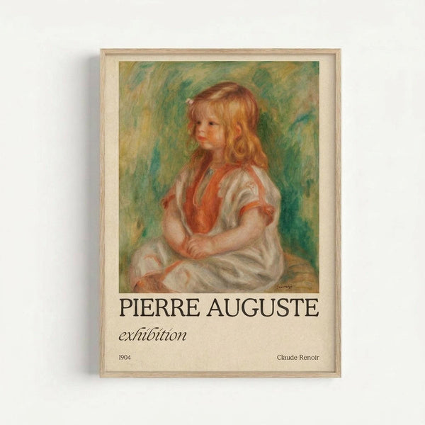 Framed art print featuring a Renoir painting of a young girl with golden curly hair wearing a white dress with coral-colored trim. The child sits in three-quarter profile against a soft green and yellow impressionist background. Below the artwork, text reads "PIERRE AUGUSTE exhibition" with "1904" and "Claude Renoir" at the bottom. The poster is displayed in a light wood frame against a white wall.