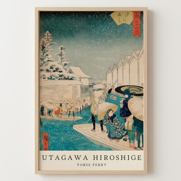 Framed Japanese woodblock print showing a snowy winter scene with people crossing a ferry in falling snow. The artwork features traditional buildings, snow-covered trees, and figures in colorful robes holding umbrellas on wooden boats crossing teal-blue water. Red cartouches with Japanese text appear in corners against a gray-green sky filled with white snowflakes. The print is displayed in a light wood frame against a white wall.