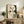 May include: Abstract geometric art print in light wood frame displayed on rustic wooden credenza. Artwork features cream, beige and dark green organic shapes with linear grid elements and circular forms. Styled with fern plant, pottery vase, books and throw pillow in warm neutral living room setting.