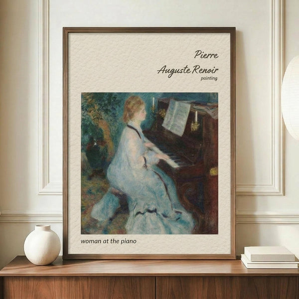 May include: Framed reproduction of Renoir's impressionist painting showing a blonde woman in a flowing white dress playing piano, displayed on a wooden sideboard next to a cream ceramic vase and stacked books against pale walls with white molding in an elegant interior setting.