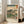 May include: Framed Japanese woodblock print artwork displayed in bright living room with beige sofa and large windows. Print features Mount Fuji in background, tall pine trees, small figures on path, and traditional landscape in muted greens, blues, and earth tones. Light wood frame rests against white wall on hardwood floor.