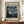 May include: Framed museum-style poster featuring Van Gogh's Starry Night painting with swirling blue sky, yellow stars, and dark cypress tree. The beige poster has "VAN GOGH" text at top and "1889" date. Display shows wooden frame on mid-century credenza with white ceramic vase and stacked books, against cream walls with white trim molding.