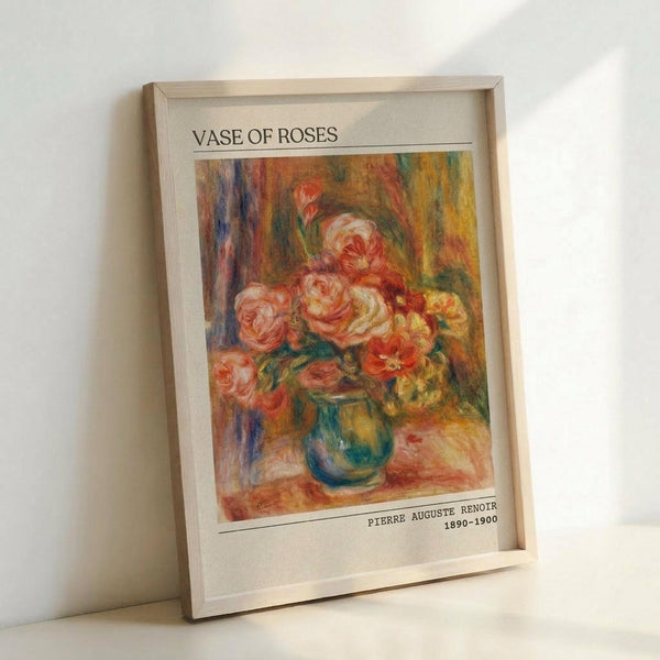 May include: Framed art print of Renoir's impressionist painting showing pink and coral roses in a blue-green vase against warm, colorful brushstrokes. The poster has "VASE OF ROSES" at top and "PIERRE AUGUSTE RENOIR 1890-1900" at bottom on white matting within a light wood frame, leaning against a white wall.